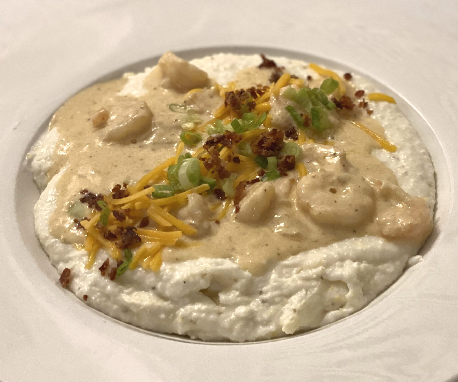 Southern Comfort Food | Darlington Country Club's Breakfast Menu Close-up of a delicious dish of grits, shrimp, savory gravy, shredded cheese, bacon bits, and chives at Darlington Country Club's dining area