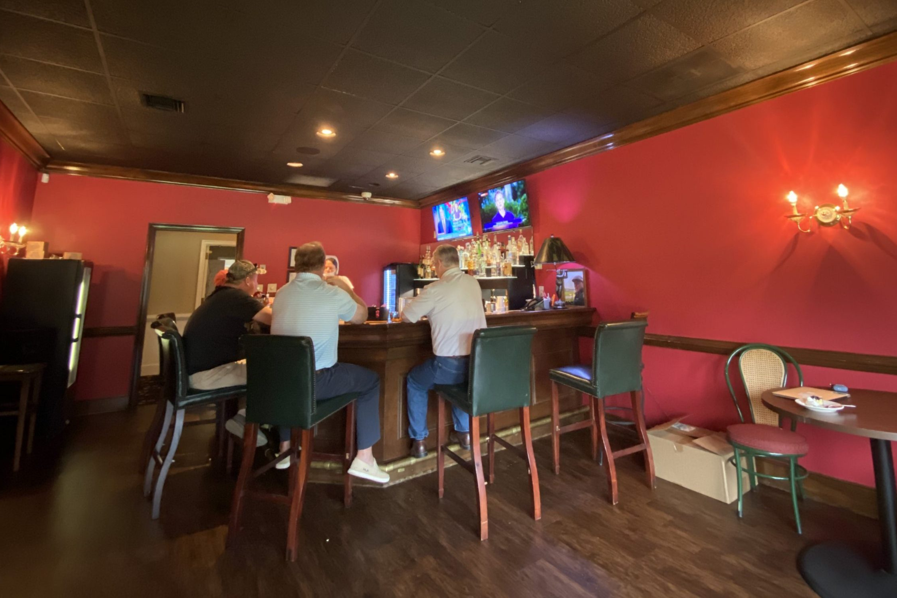 The Red Bar with red walls and three men seated watching television at Darlington Country Club