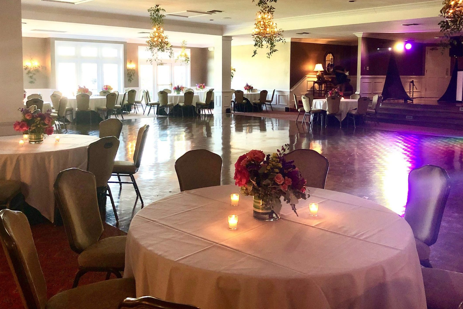 Ballroom with wooden flooring, hanging flora, and majestic dining tables at Darlington Country Club