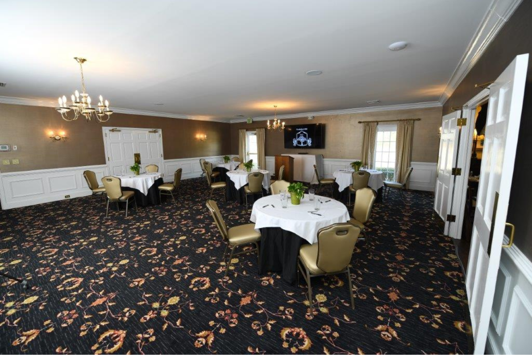Meeting room with chandeliers, a floral pattern rug, and dining areas at Darlington Country Club