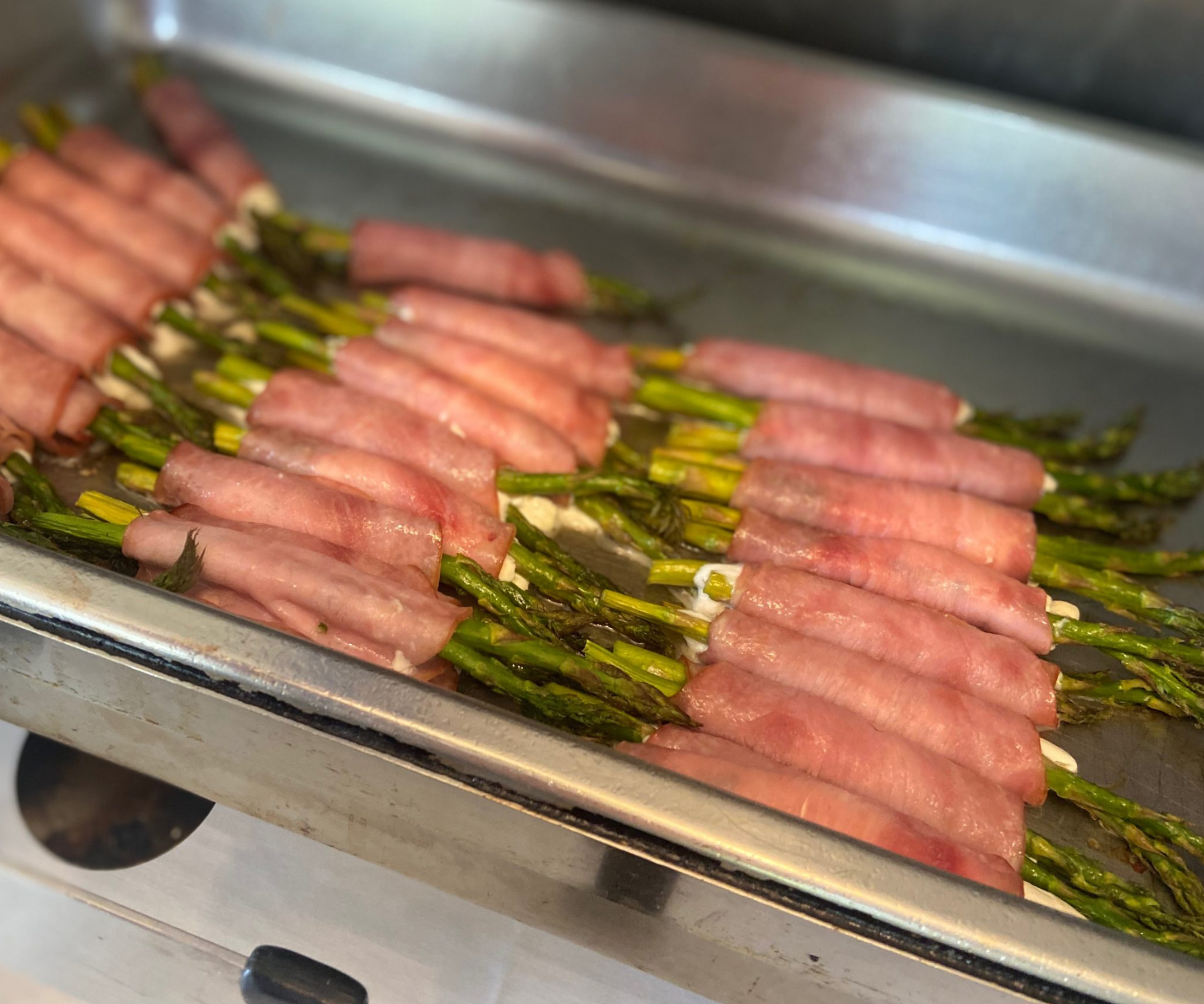 Close up of ham-wrapped asparagus and cheese on a metal platter at Darlington Country Club's dining area