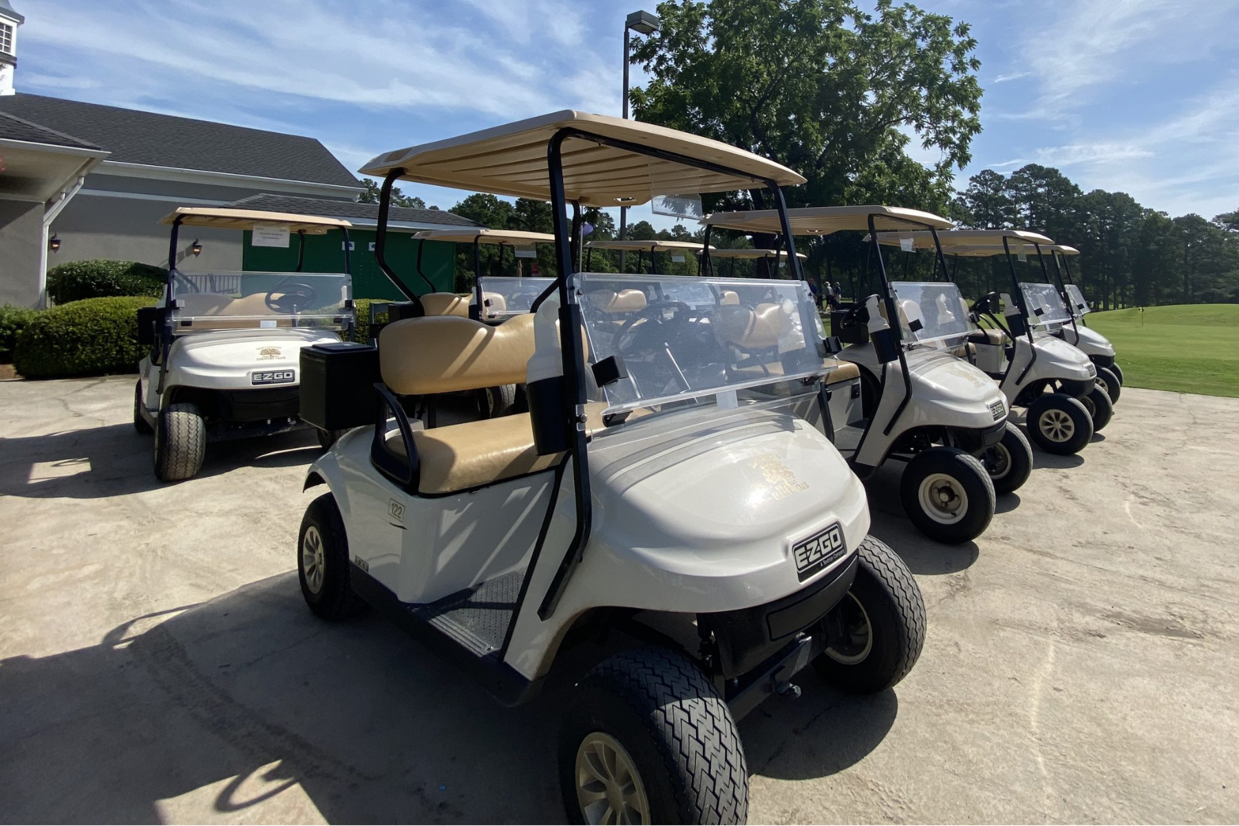 Six golf carts parked outside the Darlington Country Club clubhouse on a sunny day.