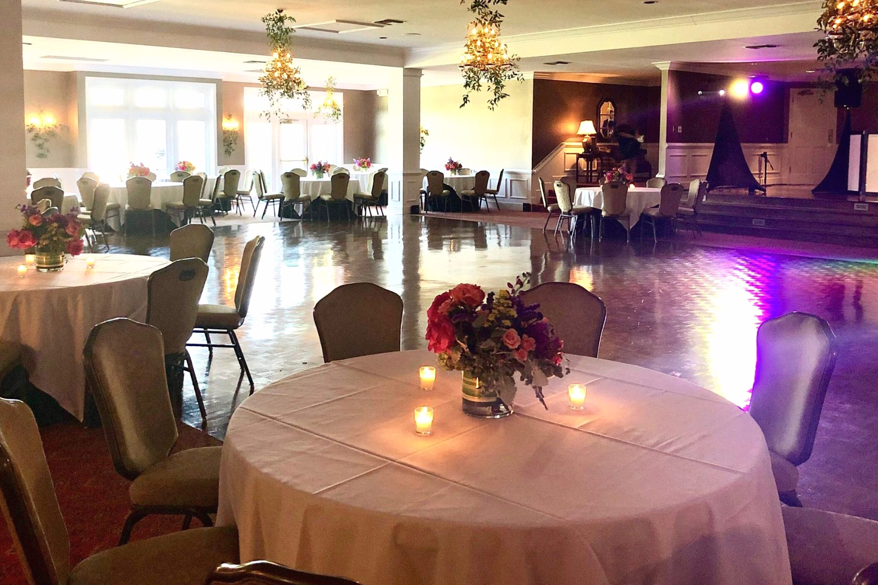 Ballroom with wooden flooring, dining tables, and hanging flora at Darlington Country Club